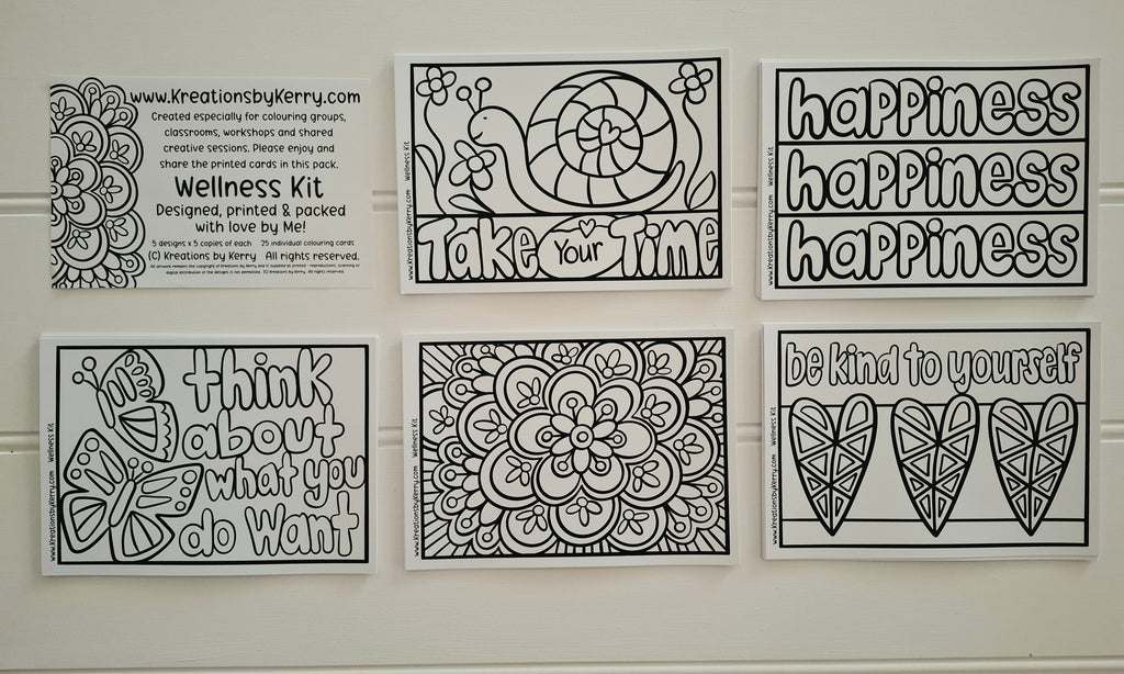 Six black and white printable coloring/meditation cards arranged in a 2x3 grid on a white wall. The cards feature phrases like 'happiness happiness happiness,' 'take your time,' 'think about what you do want,' and 'be kind to yourself,' along with floral and bird line-art designs.
