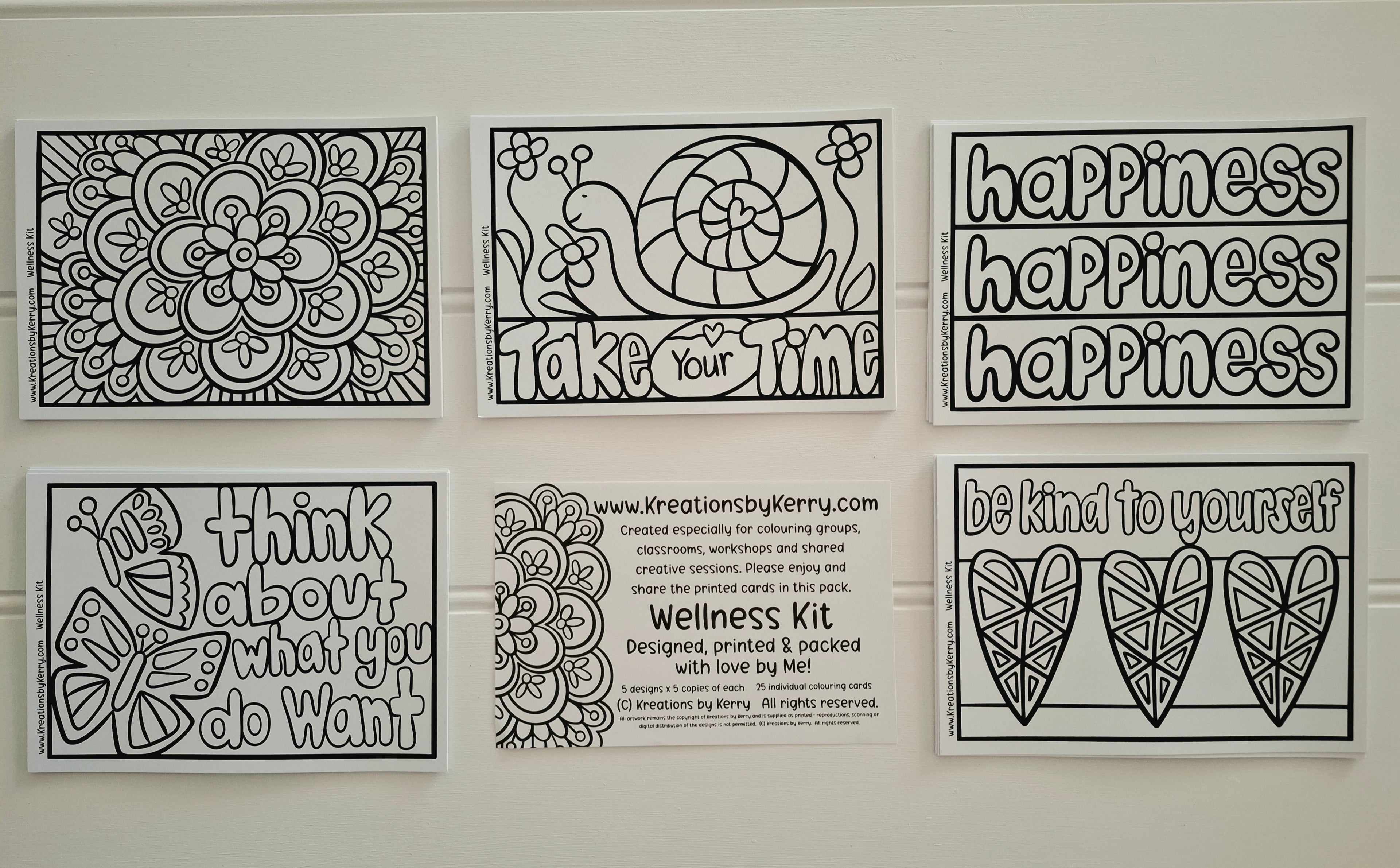 Six black-and-white printable coloring/meditation sheet designs arranged on a white wall, including floral mandala art, a snail with the word 'happiness,' motivational phrases like 'happiness happiness happiness,' a butterfly with 'Think about what you do want,' a center text panel reading 'Wellness Kit' with the website Kretationsbykerry.com, and two heart designs with 'be kind to yourself.